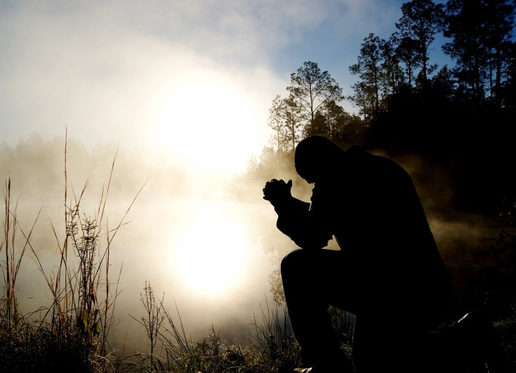 man praying in the morning at a pond