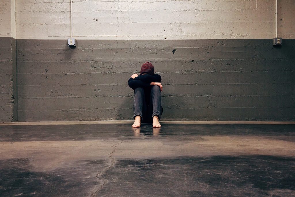 man sitting on the floor, hiding his face